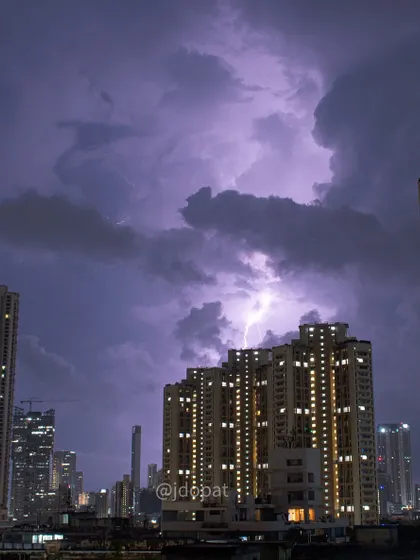 A lightning strike illuminates a massive, swirling cloud formation above Mumbai's skyscrapers during the monsoon.