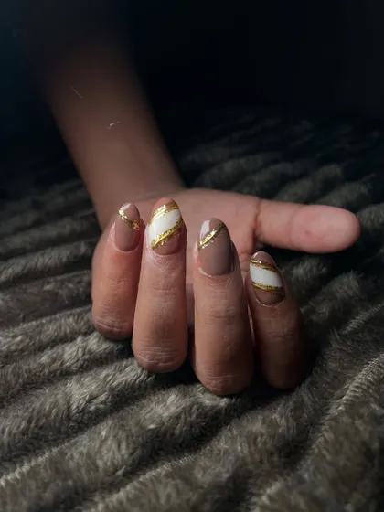This design features a nude base with bold white and gold diagonal stripes. It's a graphic and modern take on nail art that really stands out.