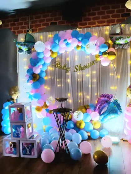 A cute and colourful baby shower setup with a pink and blue balloon arch, fairy lights, and baby-themed foil balloons. Perfect for a gender reveal or a classic baby shower party.