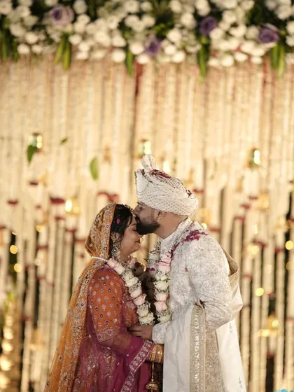 A gentle kiss on the forehead, a promise of a lifetime. The backdrop of delicate floral strings adds a touch of traditional elegance to this beautiful Varmala moment.