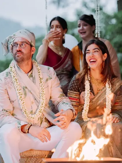 A candid moment of joy and surprise during an outdoor fire ceremony, with the couple and their guests sharing a laugh.