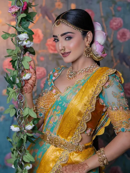 A model in a stunning South Indian Muhurtham look, featuring a turquoise and yellow saree with a heavily embroidered blouse.