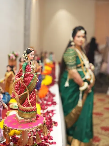 A creative shot focusing on a doll from the baby shower rukhwat, with the mom-to-be beautifully blurred in the background, connecting the miniature world to the real celebration.