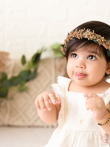 A sweet, candid close-up of a baby girl tasting frosting for the first time during her boho-themed cake smash.