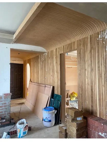 The wood-paneled wall during construction, showing how the sketch is being translated into a curved, textured surface that defines the corridor.