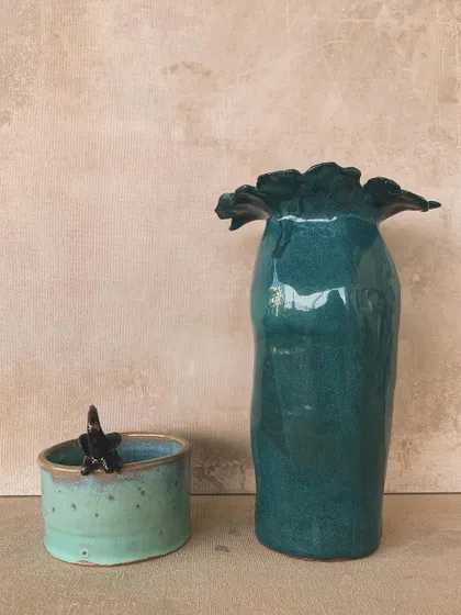 A set of two handmade vases, one a tall, glossy green piece and the other a smaller, speckled cup with a tiny black star. They look beautiful together or on their own.