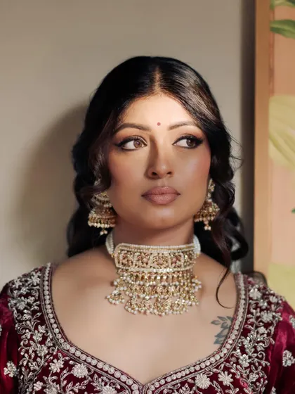 Kavi's side profile, showcasing the soft waves in her hair and the radiant finish of her makeup.