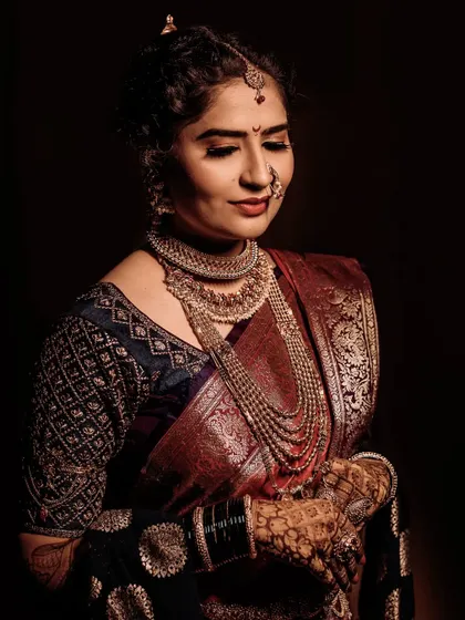 A dramatic, low-key portrait that brings all the focus to the bride. The rich colors of her saree and her calm expression create a powerful and elegant image.