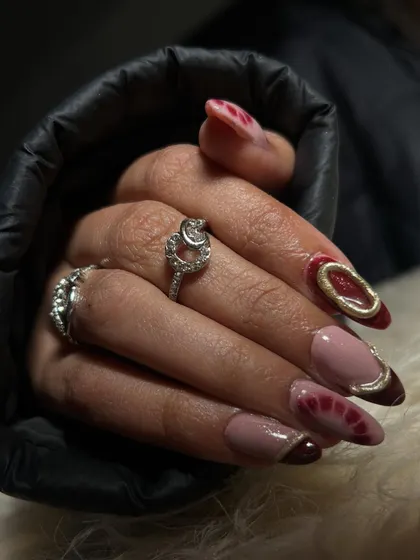 A chic and modern set of polygel extensions with a deep red and nude color palette and gold chrome accents.