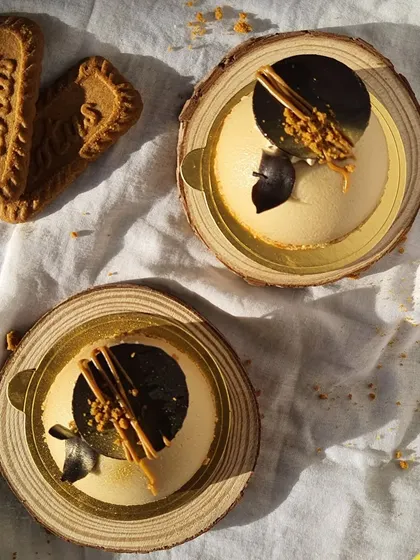 My mini cheesecakes are perfect for when you want a personal treat. Here are two of them, beautifully presented on wooden slices, showing the detailed topping of chocolate and Biscoff crumbs.