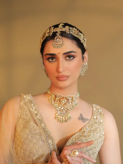 A close-up on the bride's face, highlighting the unique headpiece and the soft, glowing makeup.
