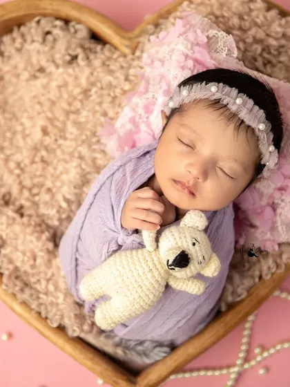 This sleeping beauty is perfectly content with her little teddy bear. The soft lighting and cozy setup ensure the baby's comfort and safety.