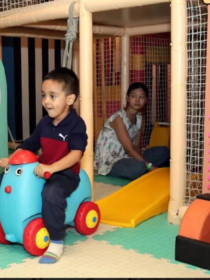 A toddler enjoys a ride on a toy car in our safe, padded play area.