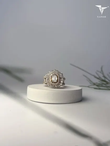 This ring, with its floral halo and radiant baguette cut center, echoes the delicate poetry of petals cast in gold and light. It is where nature inspires timeless beauty.