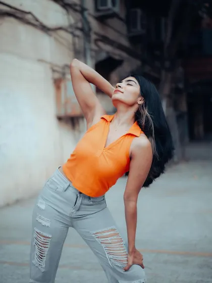 A full-length shot of a model in a casual outfit, with a dynamic pose. The urban background and her energetic stance create a lively street style image.