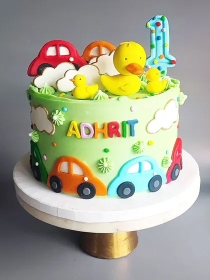 One of my most popular designs for a first birthday, this cake combines cute cars and ducks. The bright colors and playful toppers are perfect for a little one's celebration.