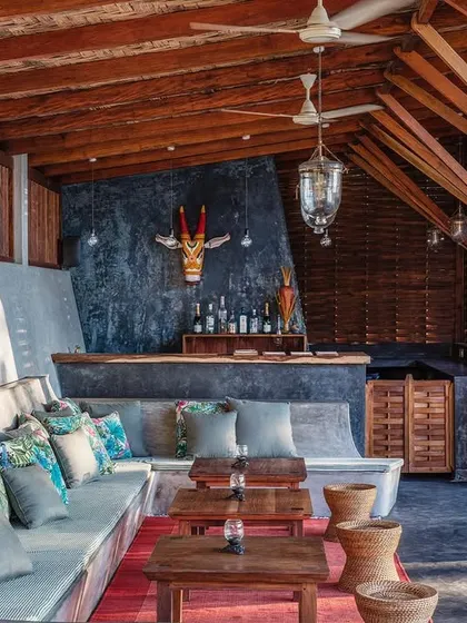 The bar and lounge area by the pool at Jalakara, with its comfortable built-in seating and rustic timber structure.