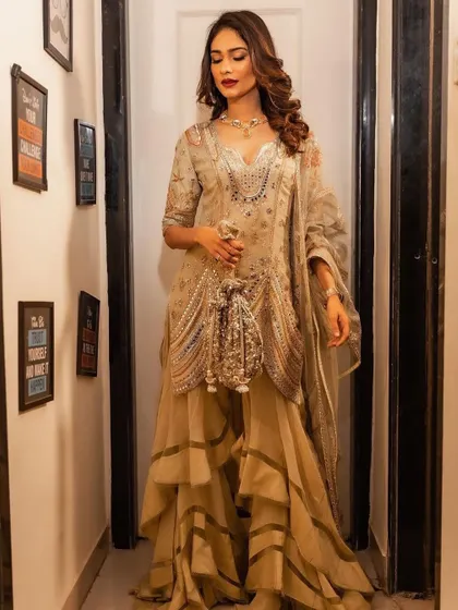 This pose highlights the rich details of the outfit. The glamorous makeup with a bold lip ensures the face is a key focal point.