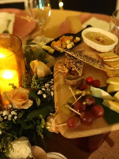 A gourmet grazing board serving as a centerpiece. This arrangement of assorted cheeses, crackers, nuts, fruits, and hummus offers a delicious and visually appealing appetizer for guests to share.