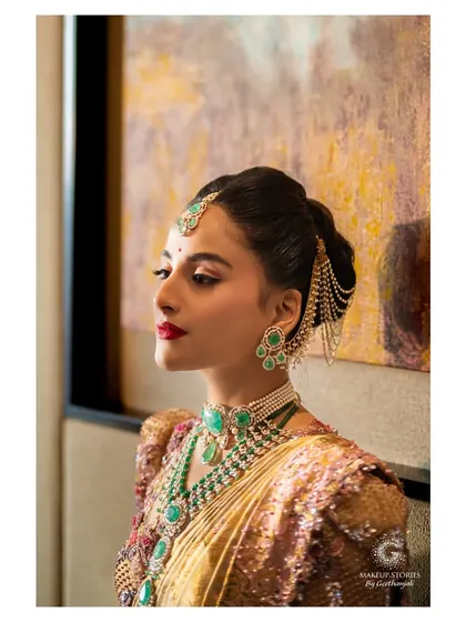 A profile view of Krishna's bridal look. The elegant hair updo is adorned with a delicate chain accessory, adding a modern twist to her otherwise traditional and royal ensemble.