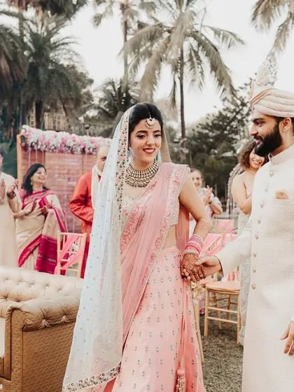 The couple's first walk together as they enter the main ceremony area, greeted by applause and happy faces.