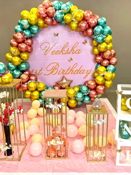 This vibrant first birthday setup features a circular backdrop framed with a garland of colorful chrome balloons. I also included pedestals for the cake and decor, along with "ONE" letter blocks for a personalized touch.