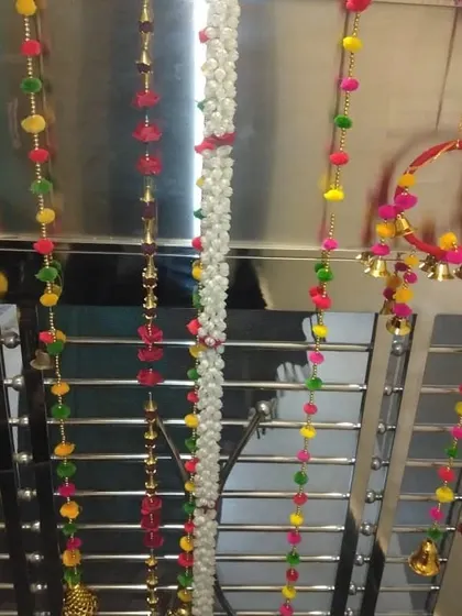 Close-up of decorative hangings with bells and colorful beads used for gate or entrance decoration.