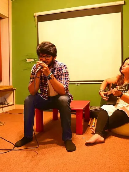 A musician playing the harmonica, accompanied by a ukulele, during one of our intimate and soulful music nights.