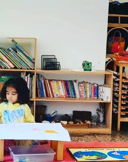 A young child works on a puzzle map of the world. After completing the puzzle, she will trace the continents and paint them, extending a simple geography lesson into a multi-step art project.