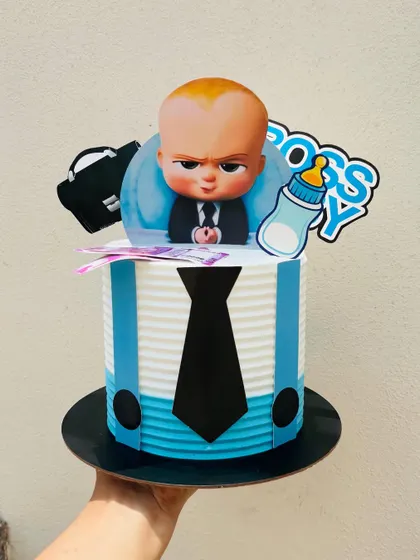 This Boss Baby cake features a shirt and tie design made with buttercream and fondant. The character topper, complete with a briefcase and bottle, finishes the look.