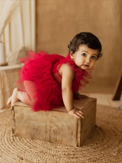 A curious toddler in a red tutu, crawling towards the camera. A fun and dynamic shot from a milestone session.
