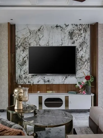 A closer view of the TV unit in the Chennai lounge. The book-matched marble panel is framed by wood and integrated shelving with brass accents, demonstrating our approach to combining different materials for a refined look.
