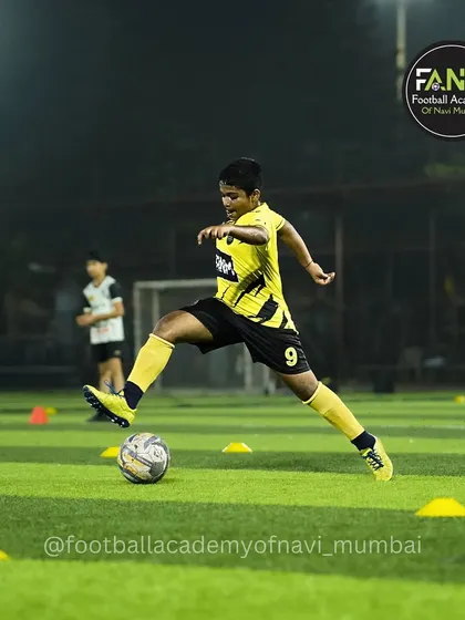 Precision in every touch. This player is fully focused on a cone drill, perfecting his ball control and footwork under the lights.