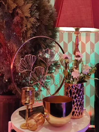 A side table vignette from the enchanted forest theme, with metallic decor pieces, a vintage lamp, and floral arrangements.