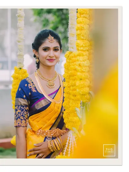 A classic portrait of the bride standing between garlands of yellow flowers, her smile radiating happiness.