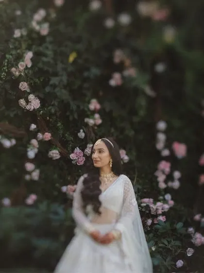 A soft-focus, artistic shot of the bride amidst a wall of flowers, creating a painterly and romantic effect.