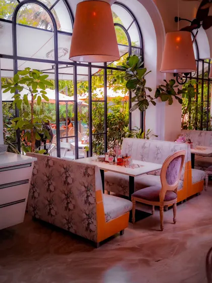 The floral-patterned booths offer a comfortable and stylish seating option. The large windows ensure the space feels open and connected to the greenery outside, even while being indoors.
