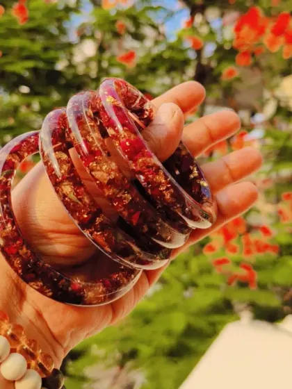 A set of custom bangles made from preserved red flowers and gold flakes encased in clear resin. Each piece is unique and handcrafted.