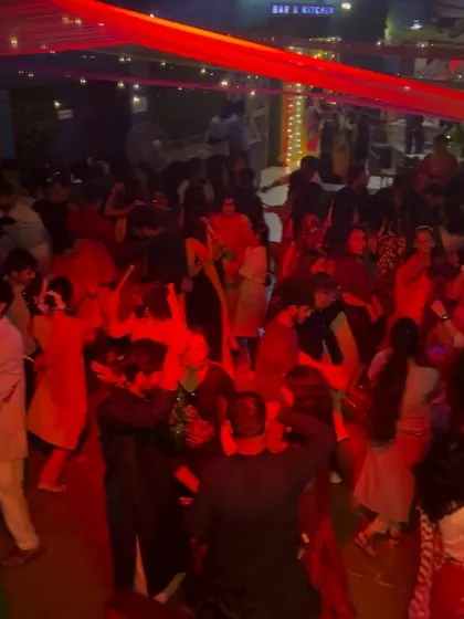 The party in full swing under red lighting, with everyone engaged in the Dandiya Raas.