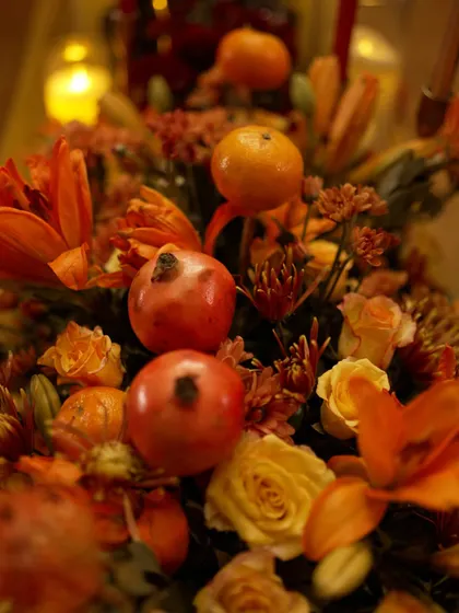 A centerpiece from the speakeasy theme, incorporating whole oranges and pomegranates into the fiery orange and red floral arrangement.