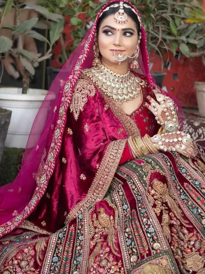 A closer look at a beautiful velvet bridal lehenga in a deep wine color. The detailed gold and multicolor threadwork makes it a piece of art.