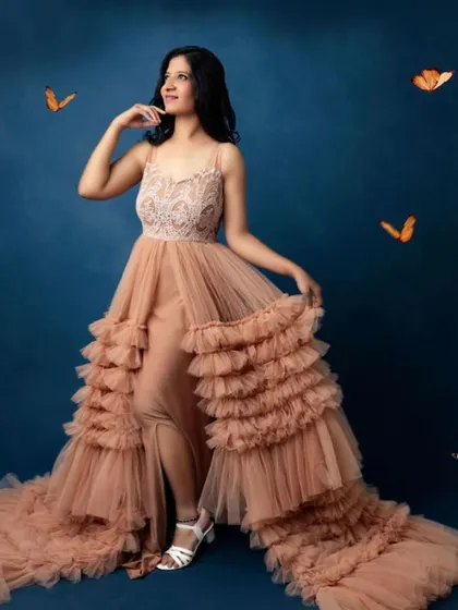 A whimsical and dreamy solo maternity portrait. The flowing gown and butterfly accents create a magical and ethereal image of a mother-to-be.