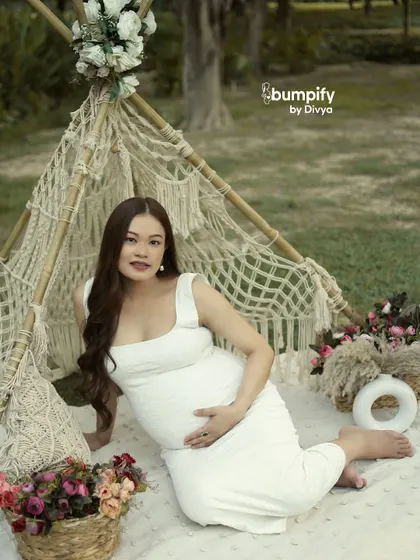 The mom-to-be smiles at the camera from her boho picnic setup. This shot showcases how we can bring a stylish, curated look to any outdoor location.