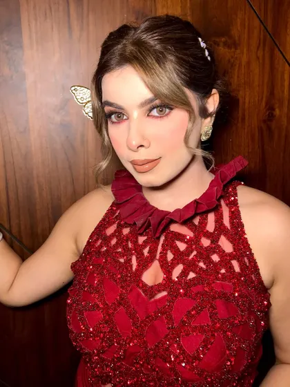 A statement look in a stunning red dress, featuring a chic knot bun and flawless glam.
