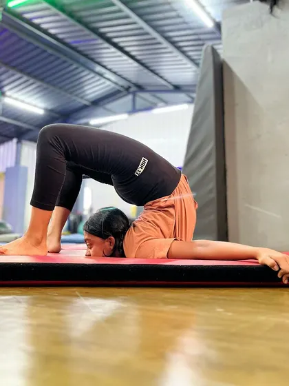 The world says fit in; the universe says stand out. This student showcases her incredible back flexibility with a deep chin stand pose.