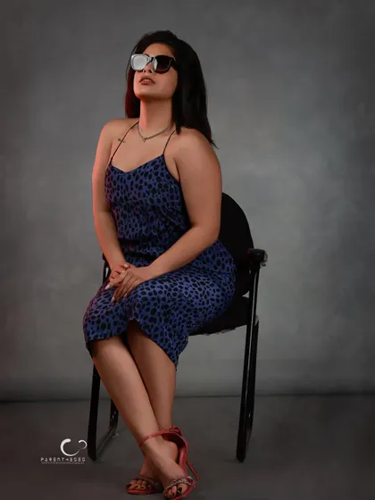 Sunglasses add an element of mystery and high fashion. This seated portrait uses subtle red-gel lighting to add warmth and dimension against the cool grey backdrop.