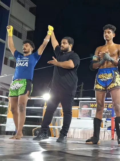 A win for Bengaluru MMA. The referee raises our fighter's arm in victory at the South Indian WMC Fight Night, a result of superior striking and conditioning.
