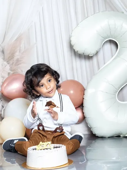 A cute moment from a second birthday shoot, with the toddler enjoying his cake.