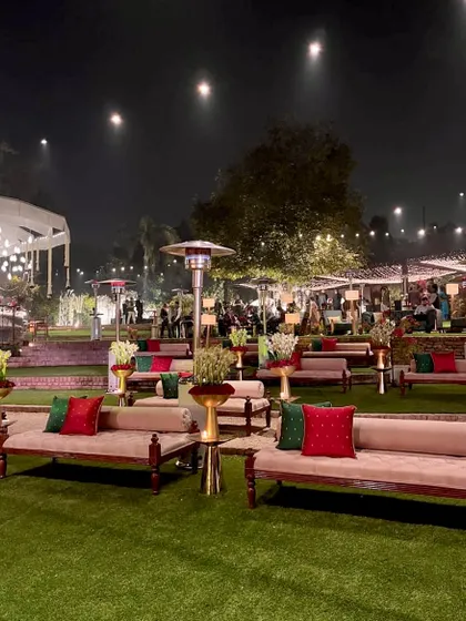 Comfortable diwan seating on the lawn, with red and green cushions, perfect for a traditional yet relaxed Mehendi or Sangeet.