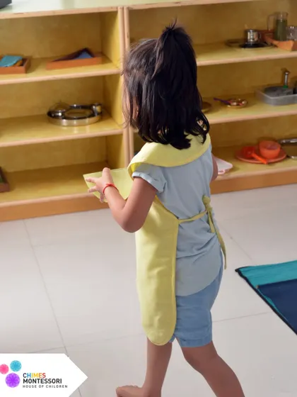 A child confidently carries her work to her mat. This is age-appropriate independence in action, a daily practice at Chimes.